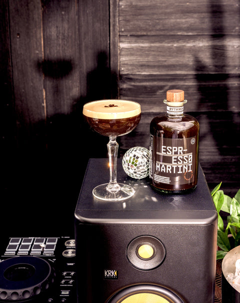 Espresso martini liqueur bottle with small martini glass on a countertop cocktail setup
