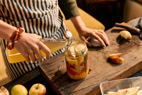 Person preparing a jar of pickled vegetables on a wooden table.