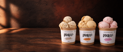 AI-styled editorial still life of Brickell’s Ricotta Stracciatella, Salted Caramel and Roasted Strawberries ice creams.