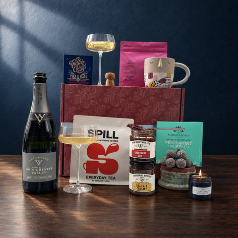 Assorted gift box with tea tin, truffles, jam jar, chocolate bar, and bottled drink