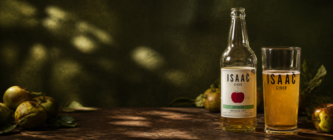 Isaac Cider Calculus bottle and glass in an art-directed orchard-inspired still life.